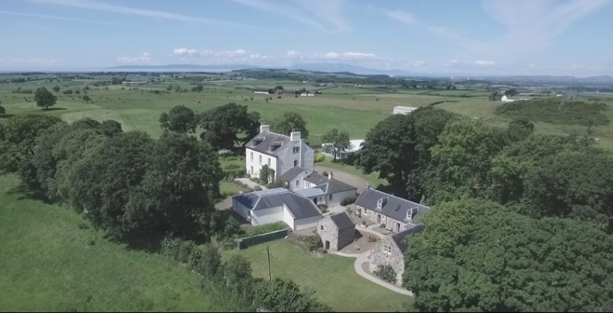 Aerial view over house and cottages looking towards sea and Isle of Arran